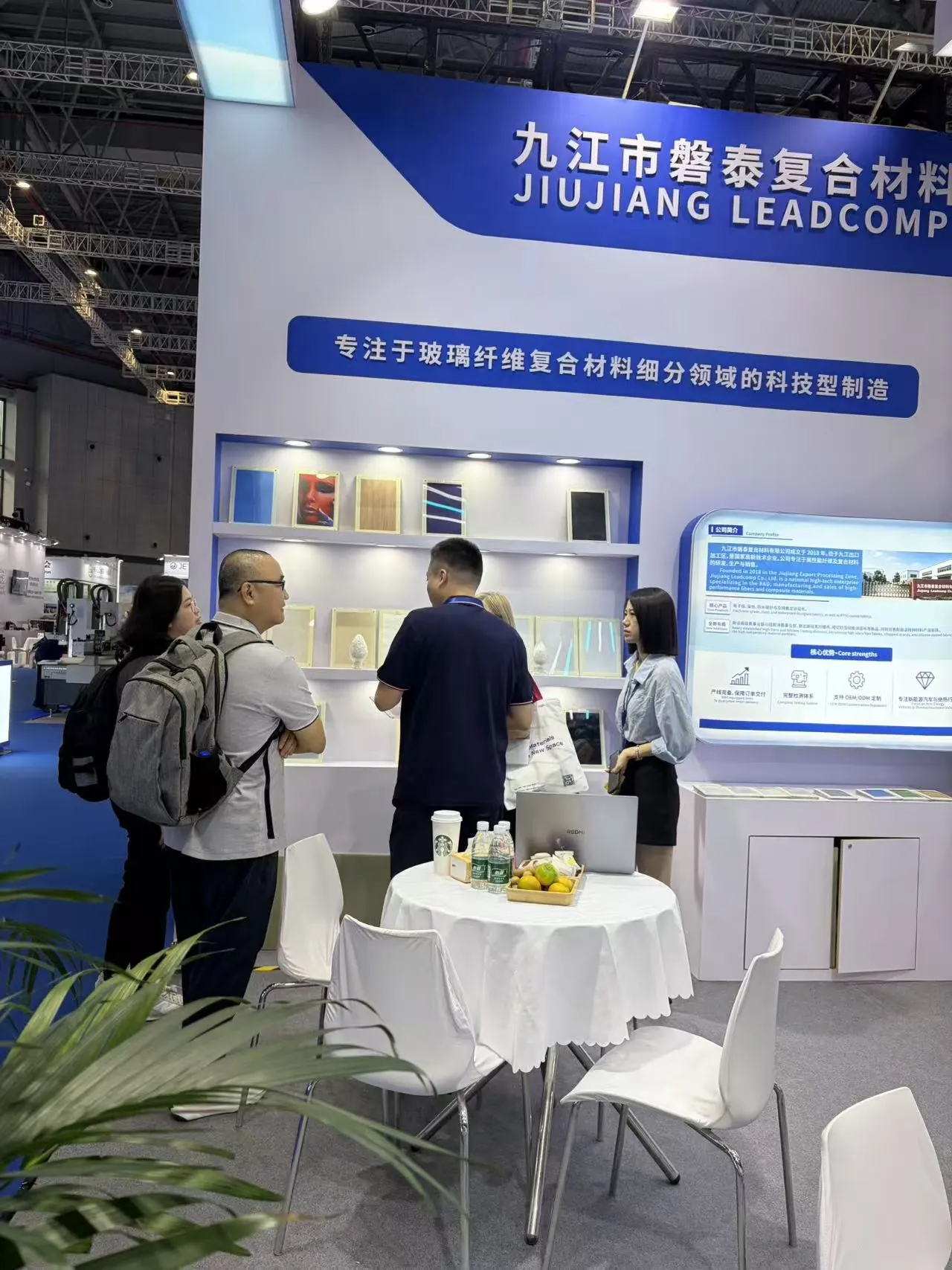 The Jiujiang Leadcomp team speaking with visitors near the fabric samples