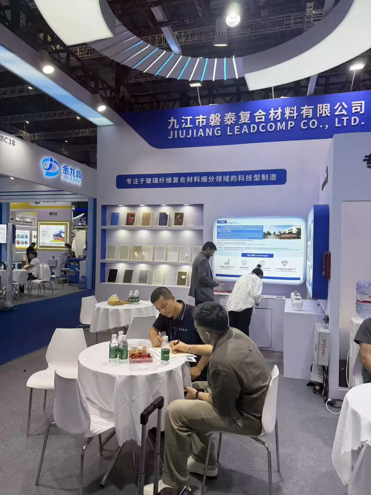 A visitor and Jiujiang Leadcomp team member reviewing information at the booth